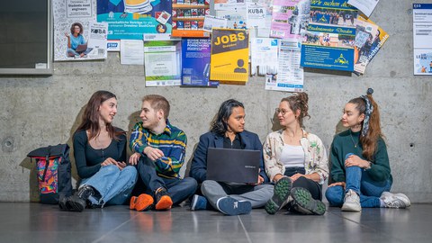 Picture of five students sitting together on the floor in a TU building and studying together.