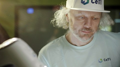 Portrait photo of Prof. Fitzek wearing a white baseball cap with CeTI's logo and looking down in concentration.