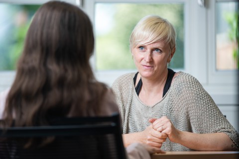 Man sieht eine Frau, die ihrem Gegenüber aufmerksam zuhört.
