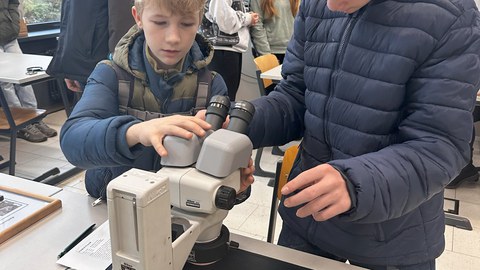 Zwei Schüler arbeiten an einem Binokular