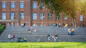 Foto von kleinen Gruppen von Personen verschiedenen Alters auf den Treppen des Fritz-Förser-Baus auf dem TUD-Campus. 