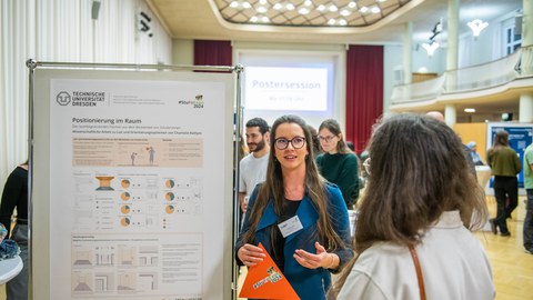 2 students talking to each other, standing next to a scientific poster