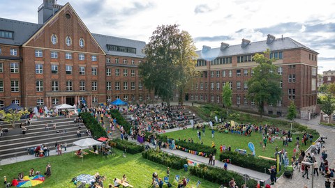 Das Foto zeigt den Innenhof des Fritz-Foerster-Baus der TUD. Zu sehen ist eine Menschenansammlung, Bastel- und Essensstände, Biertischgarnituren, bunte Wimpelketten.