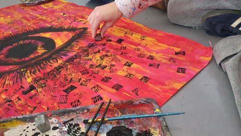 An eye on a red background is painted by a student.