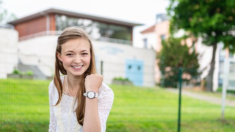 Eine Frau die lächelt und die Faust erhoben nach oben streckt.