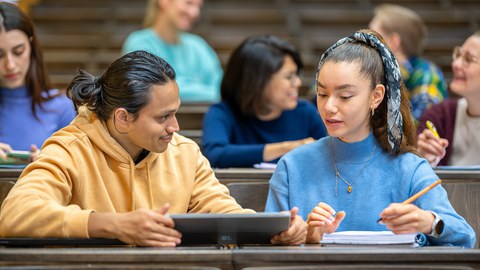 Photo of seven students in the TUD lecture hall. They are working together or chatting.