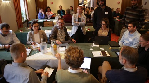 Gruppe von Menschen, die um einen Tisch herum sitzen und sich unterhalten