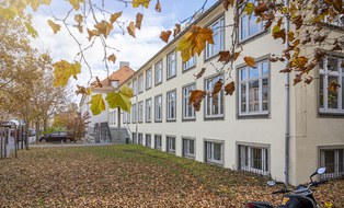 This photo shows the Günther Landgraf Building at TU Dresden. The lawn in front of the building is covered with leaves
