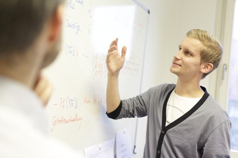 Ein Studierender erläutert Studieninhalte an der Tafel.
