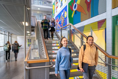 Foto von Studierenden, die eine Treppe gemeinsam herunterlaufen