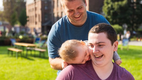 Foto eines lachenden Paares mit einem Kleinkind beim Familienfest der TU Dresden am Fritz-Foerster-Bau.