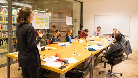 Eine Gruppe Studierender sitzt in einem Arbeitsraum der SLUB zusammen in einem Workshop des Schreibzentrums.