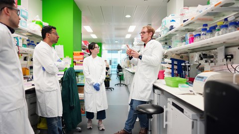 Mehrere Menschen stehen im Labor und sprechen miteinander.