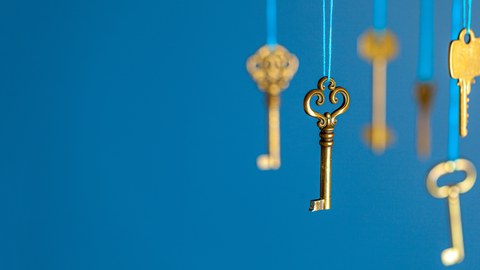 Many old keys of yellow gold color are hanging on thread on a blue background. The concept of the selection of access or password to the secret data. 