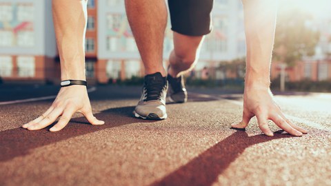 Muskel, Hände, Sonnenlicht, Beine in Turnschuhen eines starken Mannes am Morgen im Stadion. Vorbereitung am Start.