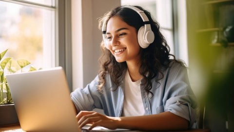 Woman using laptop and drinking beverage in bed