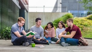 Photo: Five happy students sitting on a wooden terrace of the Andreas Pfitzmann Building