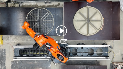 Standbild aus dem verlinktem Video, 2 Roboterarme die Bauteile herstellen, 1 Arm druckt Beton, der andere setzt Bewehrungselemente ein